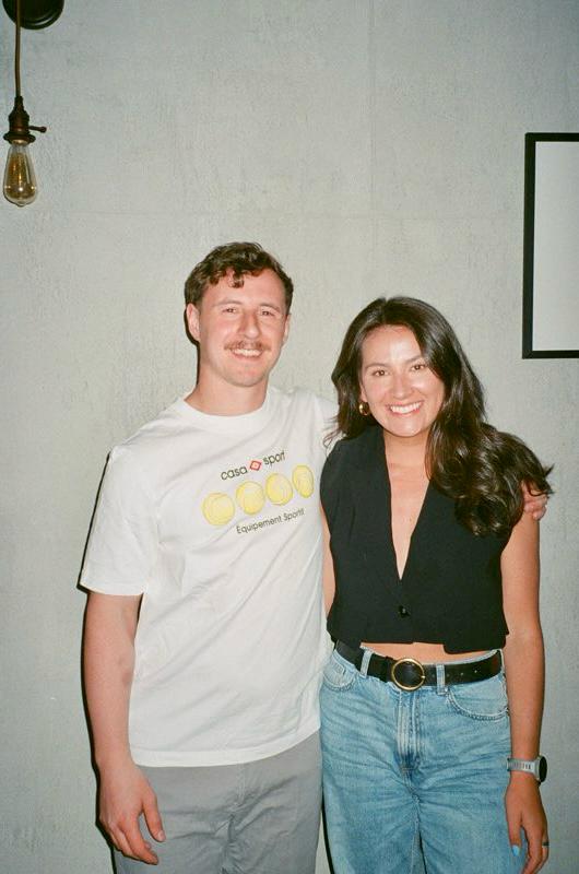 Mary and Hunter standing together against a pale wall.